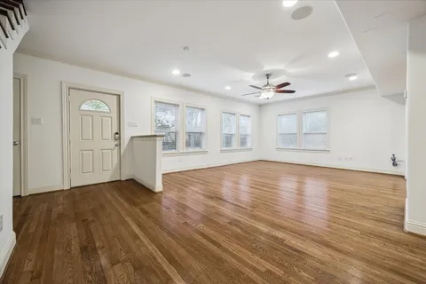an empty room with wooden floor cabinet and windows
