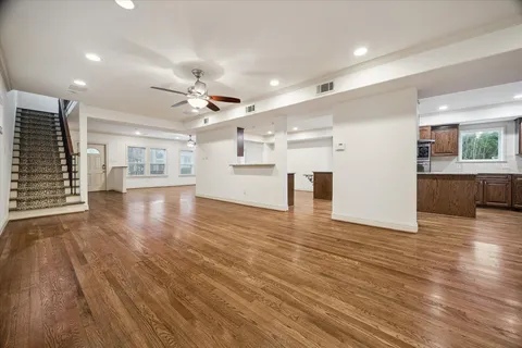 a view of empty room with wooden floor and kitchen view