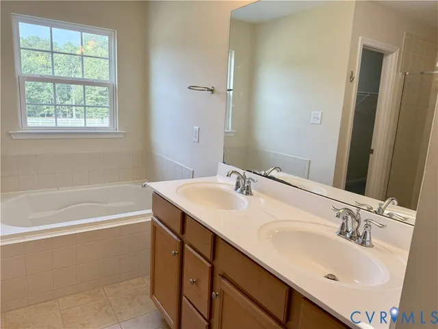 a bathroom with a sink double vanity granite tub shower and a mirror