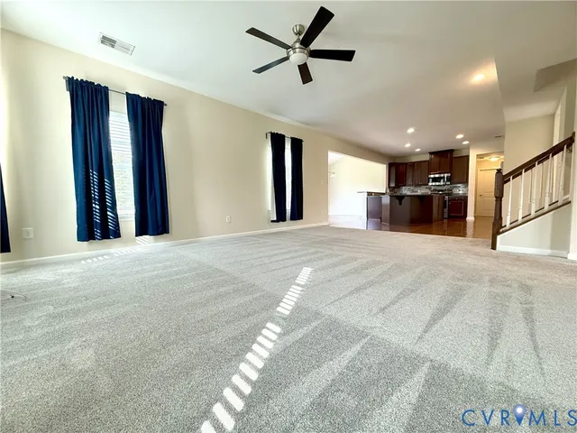 a view of a livingroom with a ceiling fan & kitchen space