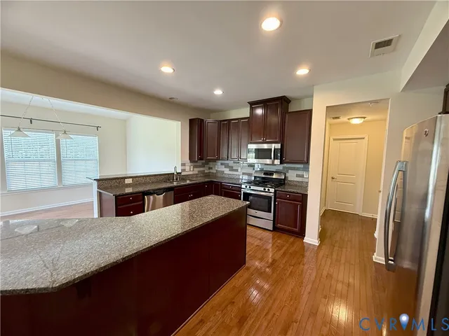 a large kitchen with granite countertop a large counter top stainless steel appliances and cabinets