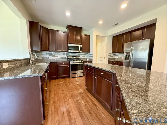 a large kitchen with stainless steel appliances granite countertop a stove refrigerator and a sink