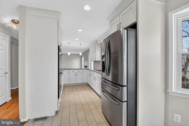 a kitchen with granite countertop white cabinets a sink a window and stainless steel appliances