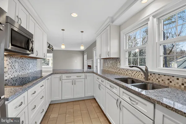 a kitchen with granite countertop white cabinets stainless steel appliances and a counter space