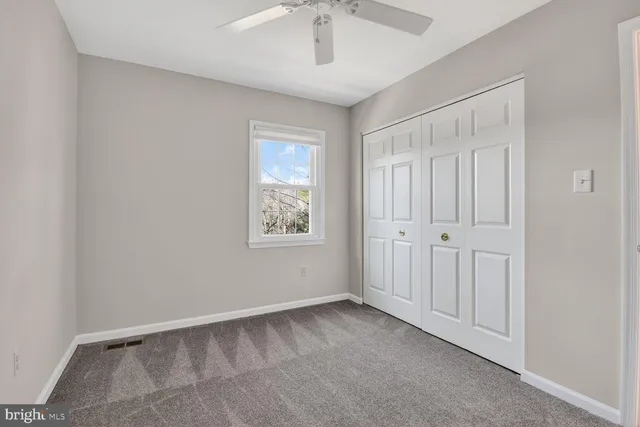 a view of an empty room with wooden floor and ceiling fan