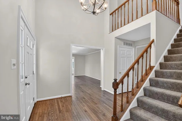 a view of staircase with wooden floor and a chandelier