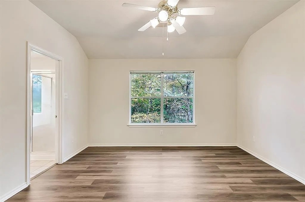 2 Peach Ridge Place The Woodlands, TX 77382 - Photo 17 of 29 an empty room with wooden floor chandelier fan and windows