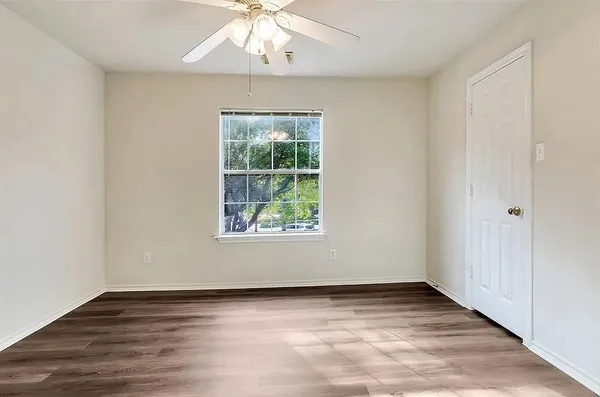 an empty room with wooden floor chandelier and window