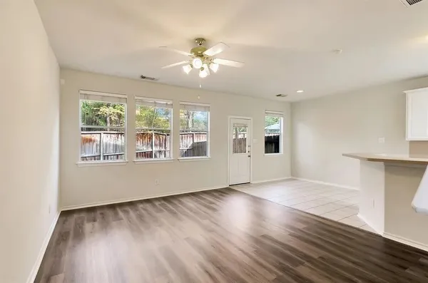 a view of an empty room with wooden floor and a window
