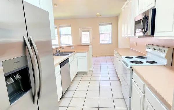 a kitchen with granite countertop a stove a sink and a refrigerator