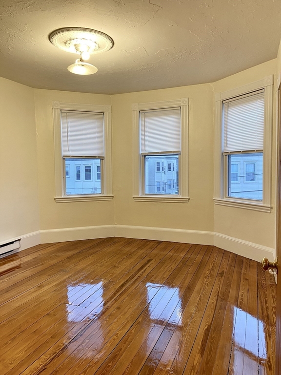 257 Beacon Street, Unit 3 Somerville, MA 02143 - Photo 2 of 15 a view of an empty room with wooden floor and a fan