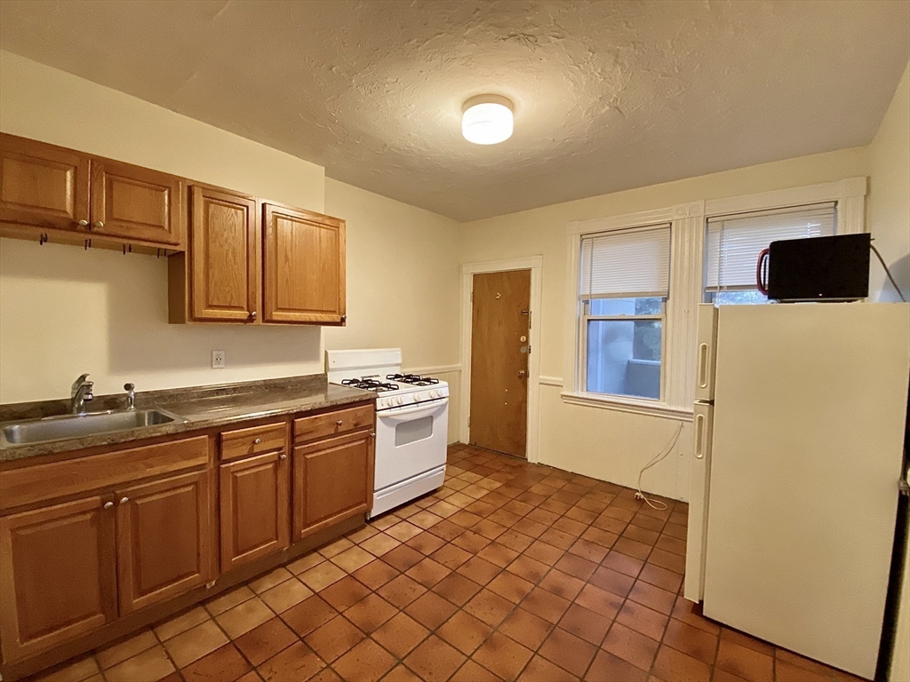 257 Beacon Street, Unit 3 Somerville, MA 02143 - Photo 7 of 15 a kitchen with stainless steel appliances granite countertop a refrigerator and a sink