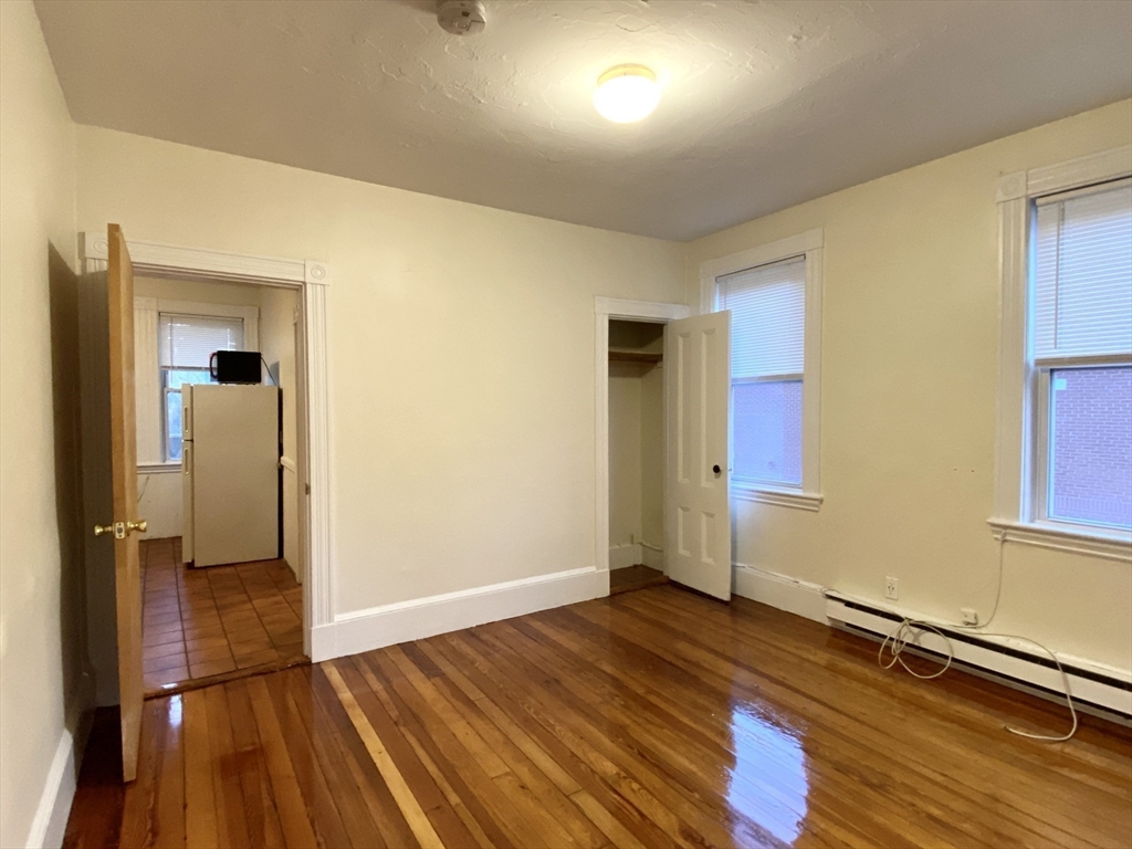 257 Beacon Street, Unit 3 Somerville, MA 02143 - Photo 9 of 15 an empty room with wooden floor and windows