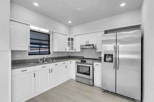 a kitchen with granite countertop stainless steel appliances and white cabinets