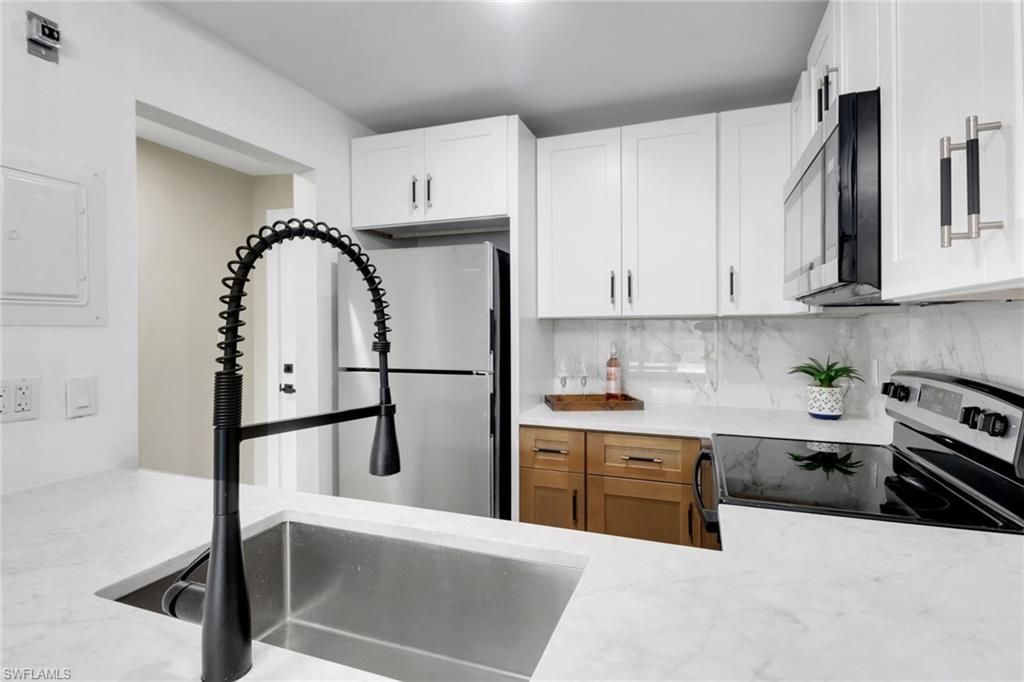 a kitchen with kitchen island granite countertop a sink a stove and cabinets