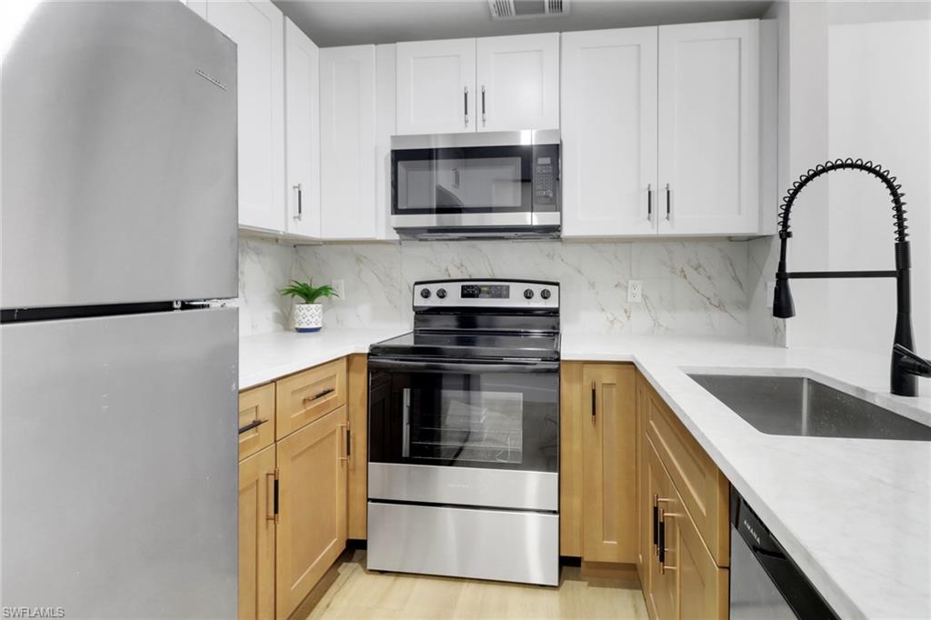 1195 Clam Court, Unit 202 Naples, FL 34102 - Photo 5 of 5 a kitchen with granite countertop white cabinets and stainless steel appliances