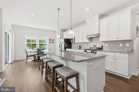 a kitchen with stainless steel appliances granite countertop a stove a sink dishwasher a microwave oven a stove with white cabinets and wooden floor
