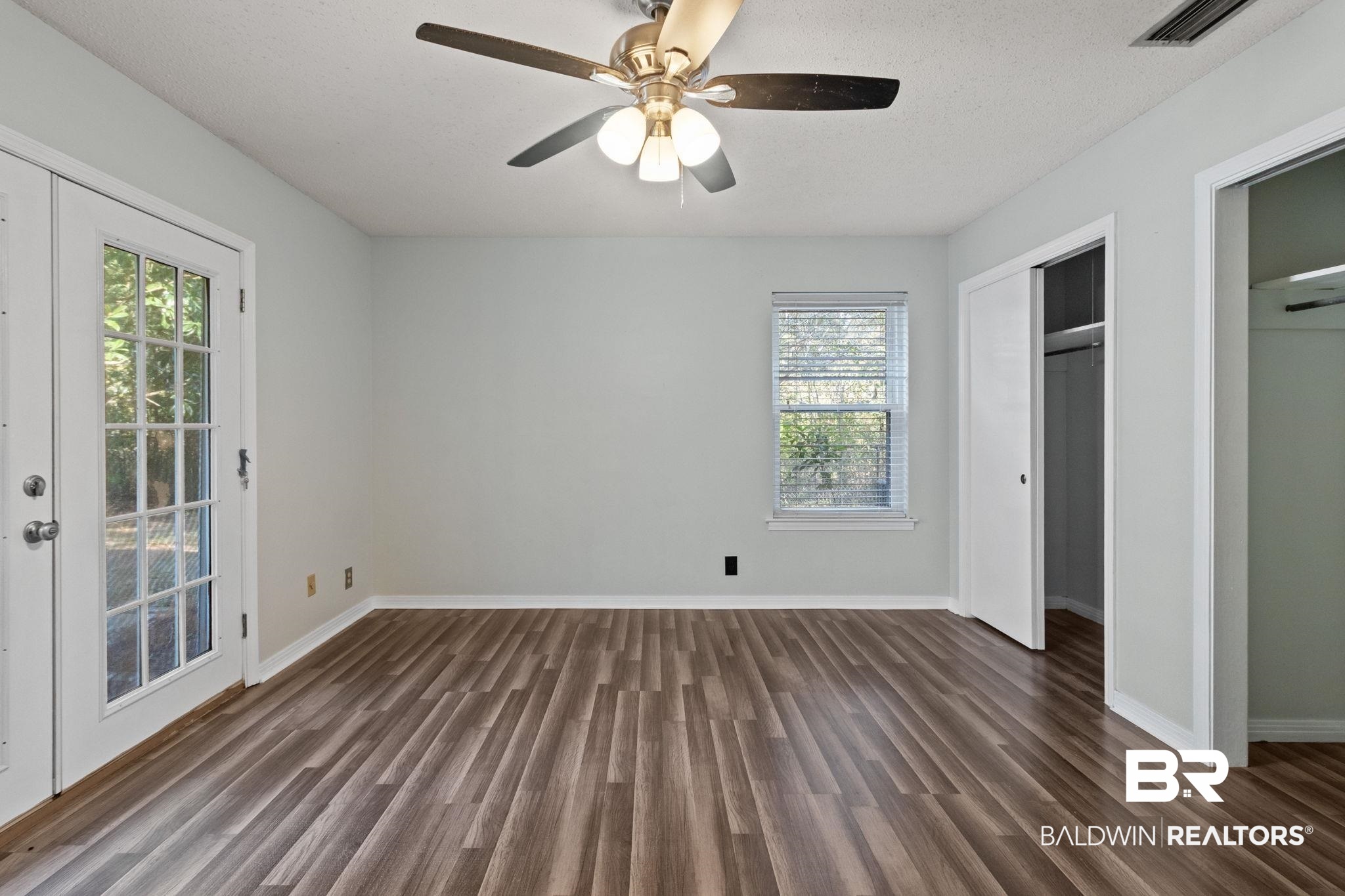 3864 Leroy Stevens Road Mobile, AL 36619 - Photo 16 of 33 Unfurnished bedroom with dark wood finished floors, two closets, ceiling fan, french doors, and a textured ceiling