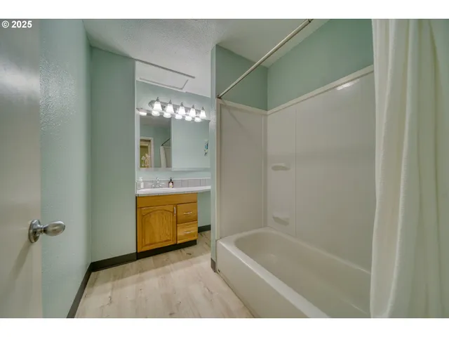 a bathroom with a tub shower sink and mirror