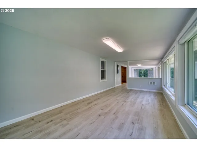 a view of a big room with wooden floor and windows