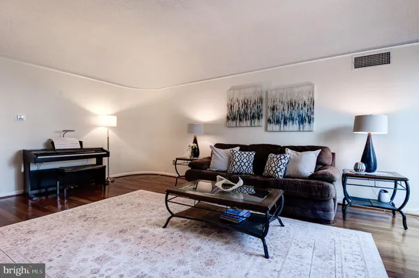 a living room with furniture and a piano next to a window