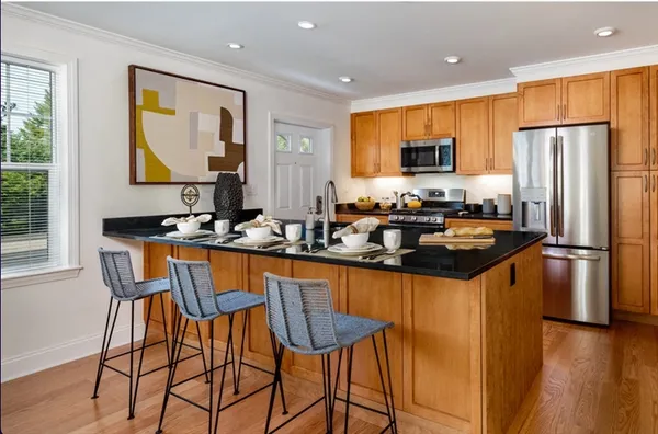a kitchen with stainless steel appliances granite countertop a sink a stove a refrigerator a dining table and chairs