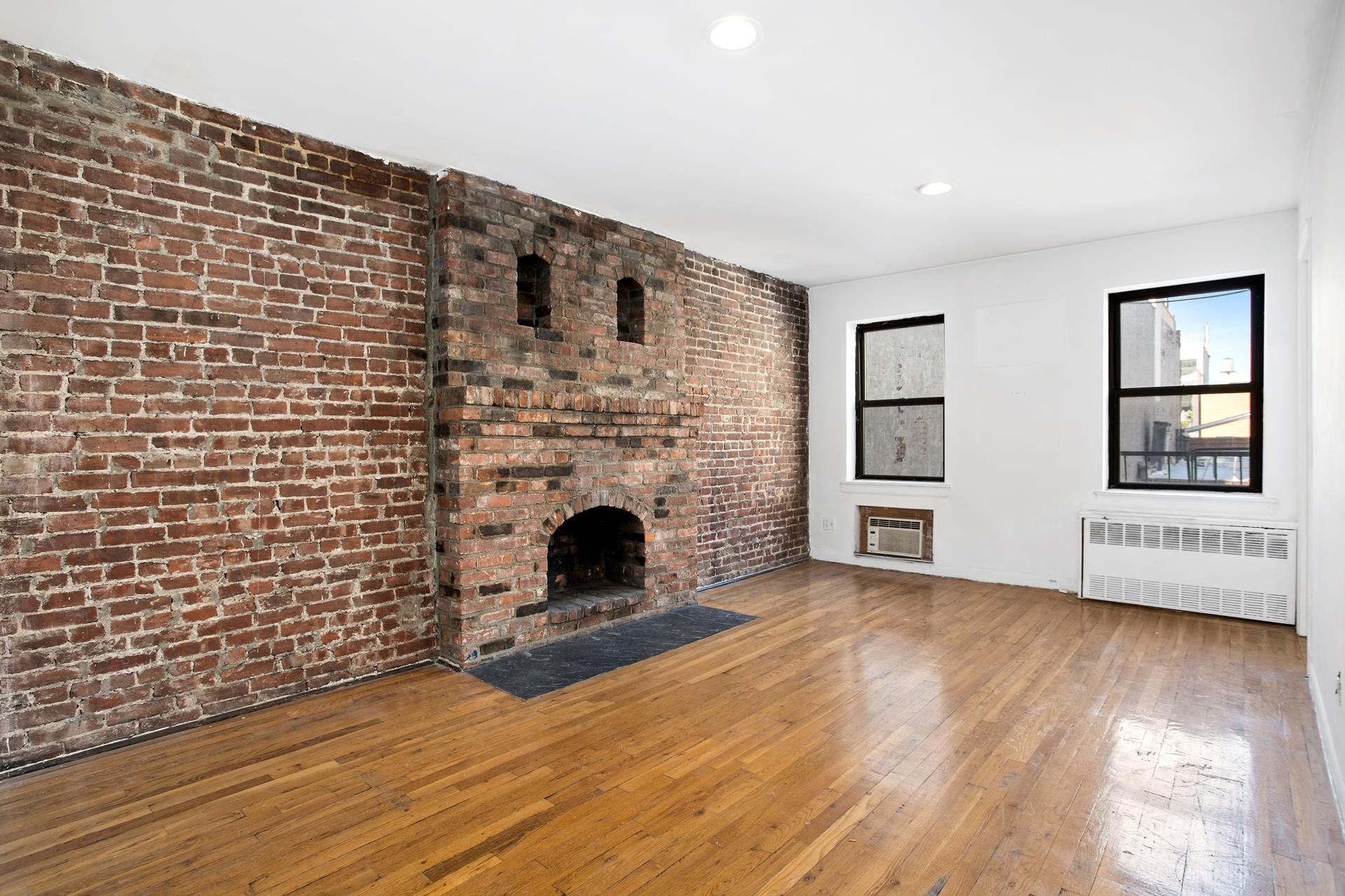 a view of empty room with a fireplace and wooden floor