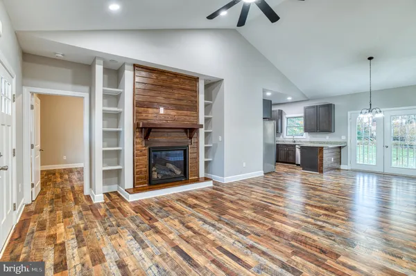a view of a livingroom with a fireplace a ceiling fan and wooden floor