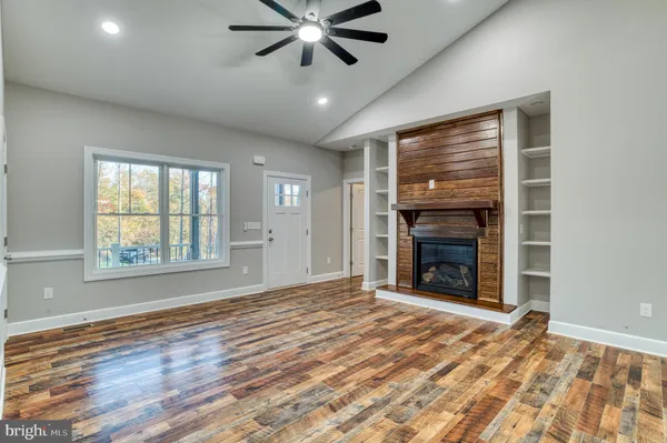 an empty room with windows fireplace and wooden floor