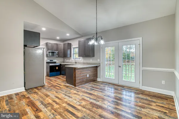 a large kitchen with kitchen island a island wooden floor stainless steel appliances and cabinets