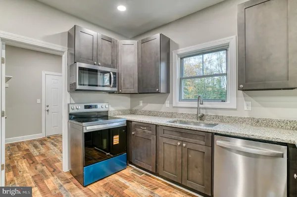 a kitchen with stainless steel appliances granite countertop a sink stove and microwave