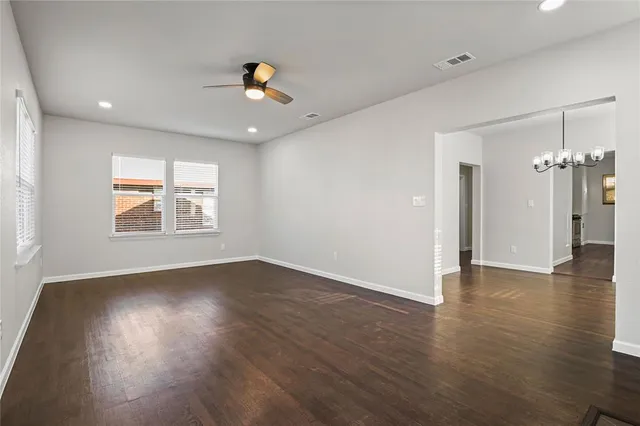 an empty room with wooden floor chandelier and windows