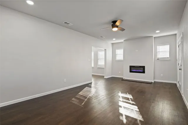 an empty room with wooden floor chandelier and windows