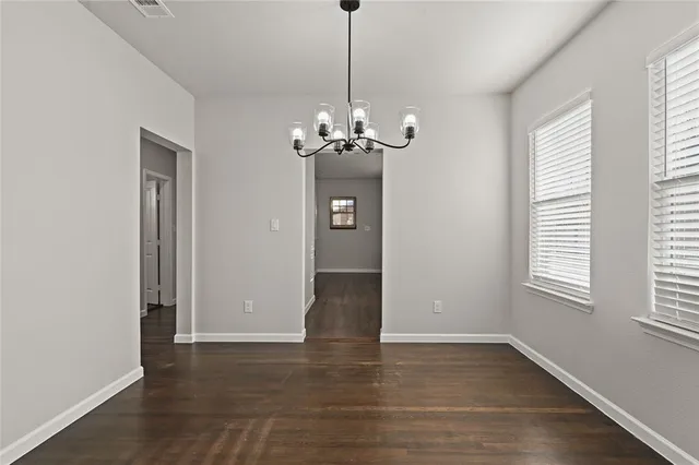 a view of a room with wooden floor chandelier and windows