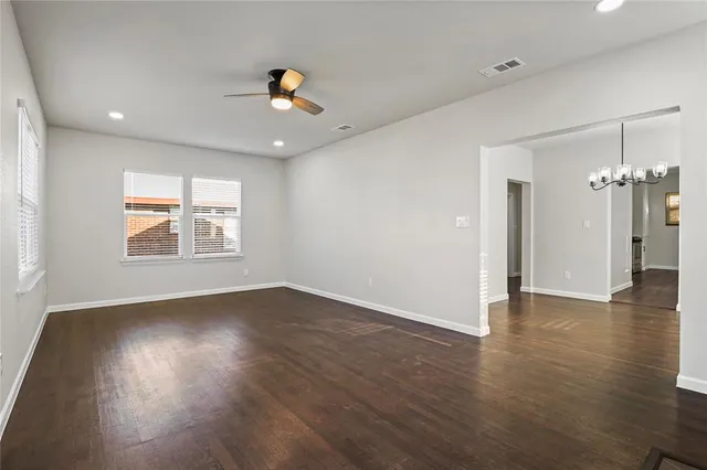 an empty room with wooden floor chandelier and windows