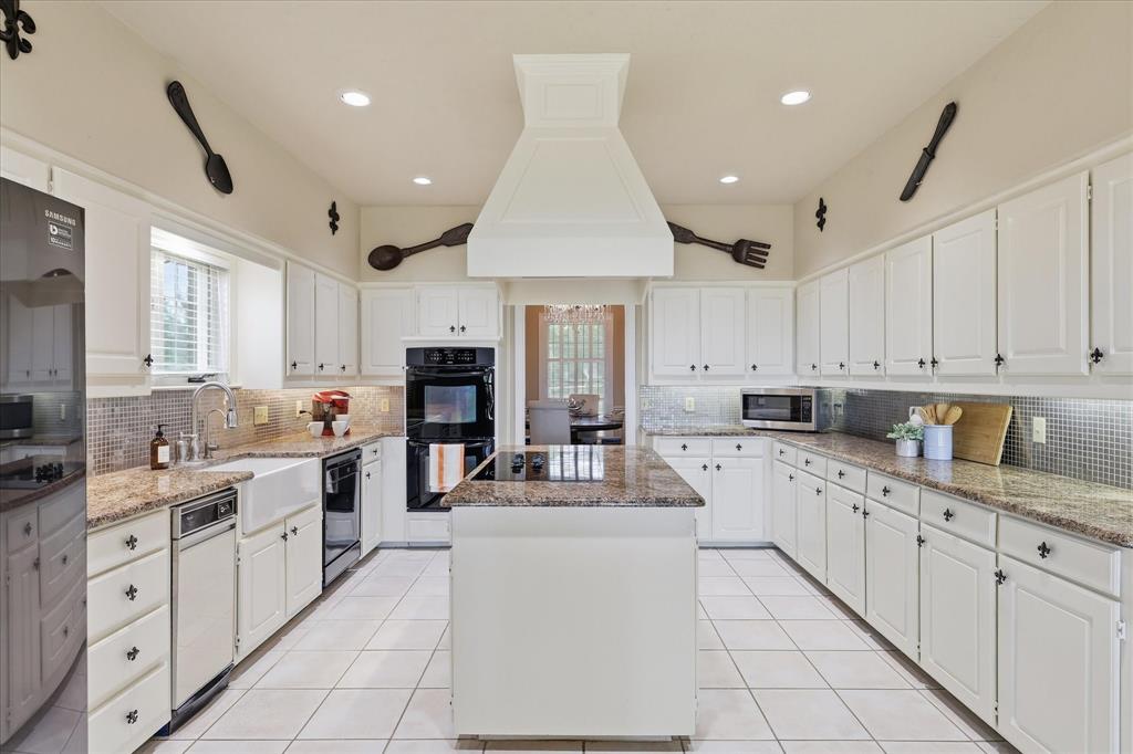 6955 Hawk Road Flower Mound, TX 75022 - Photo 16 of 40 Expansive kitchen featuring white cabinetry, granite countertops, a central island, double wall ovens, and a farmhouse sink