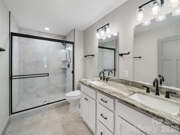 a bathroom with a granite countertop sink a toilet and a mirror