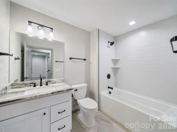 a bathroom with a granite countertop sink toilet a large mirror a bathtub and shower