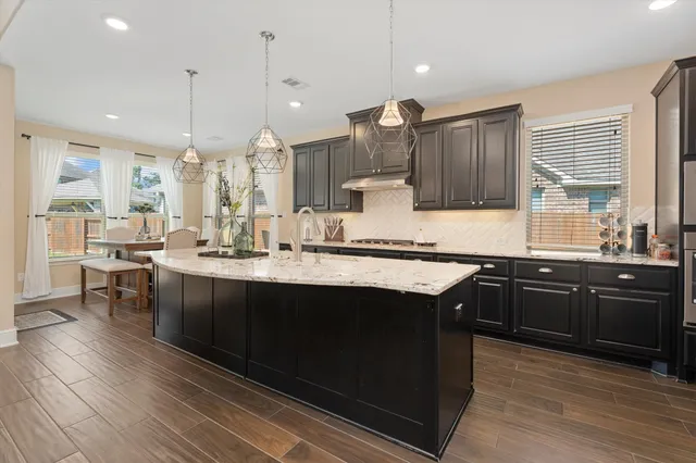 a kitchen with kitchen island granite countertop a sink cabinets and wooden floor