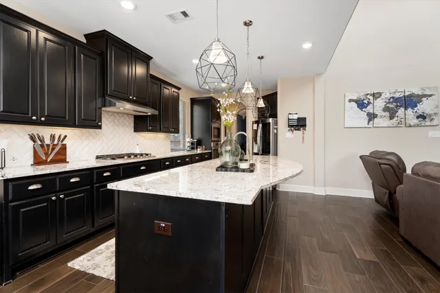 a kitchen with granite countertop a table chairs stove a refrigerator and cabinets