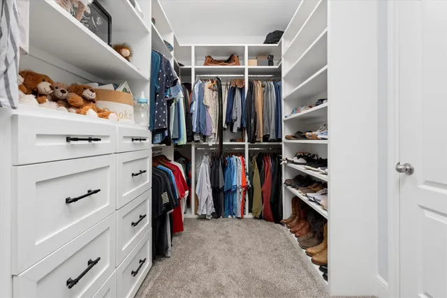 a view of walk in closet with clothes and shoes