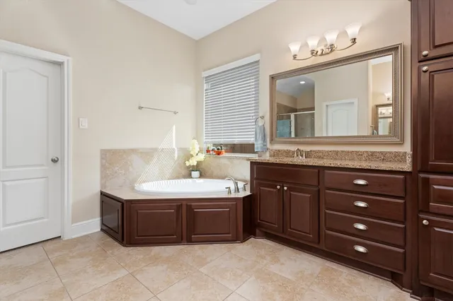 a spacious bathroom with a granite countertop double vanity sink and mirror
