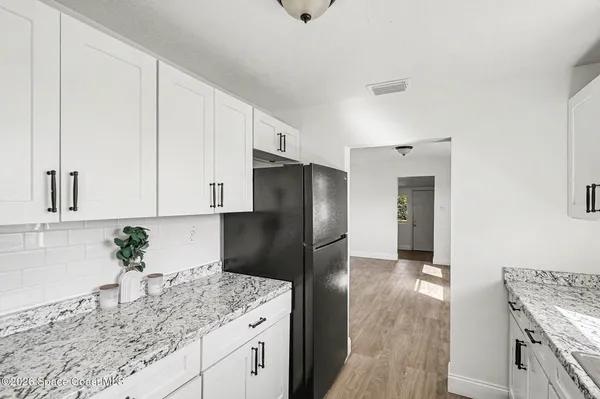 a kitchen with stainless steel appliances granite countertop a refrigerator a sink and white cabinets