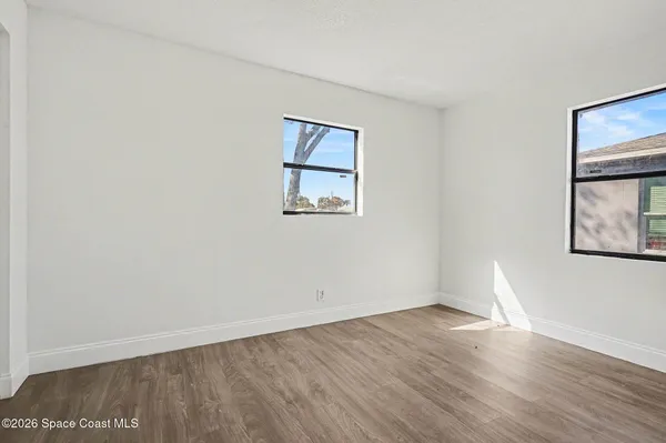 an empty room with wooden floor and windows