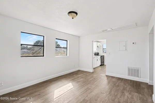 a view of empty room with wooden floor and window