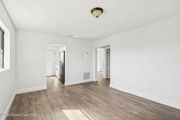 a view of an empty room with wooden floor and a window