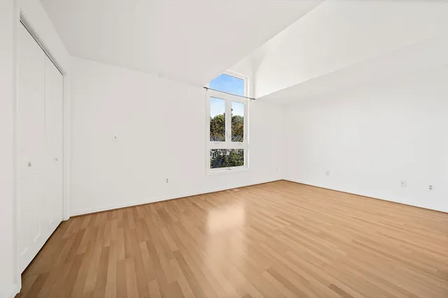 an empty room with wooden floor and windows