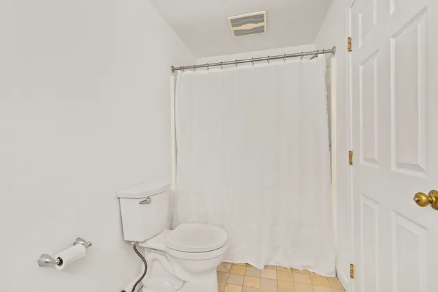 a white toilet sitting next to a shower
