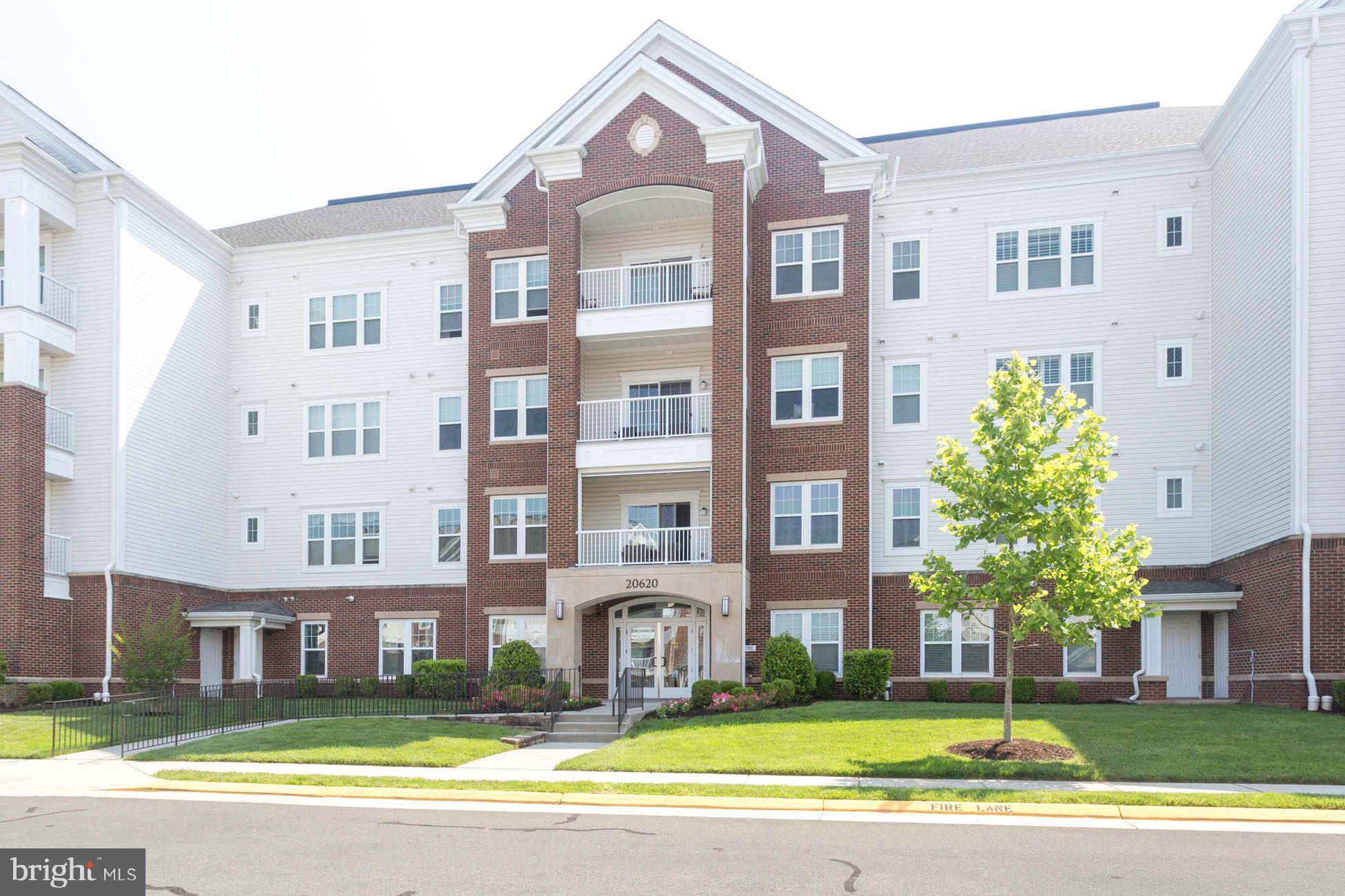 20620 Hope Spring Terrace, Unit 303 Ashburn, VA 20147 - Photo 1 of 34 a front view of a building with a garden and plants