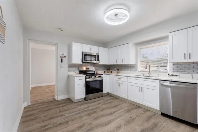 a kitchen with granite countertop white cabinets and stainless steel appliances